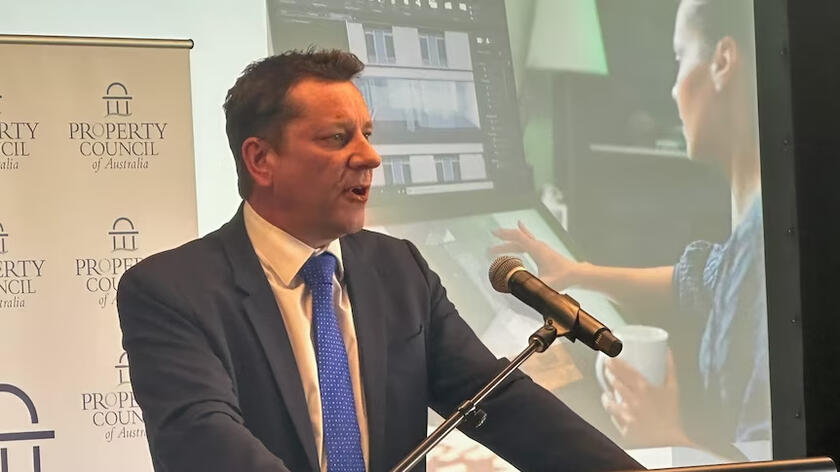 An man making a presentation in front of a screen showing artificial intelligence in planning